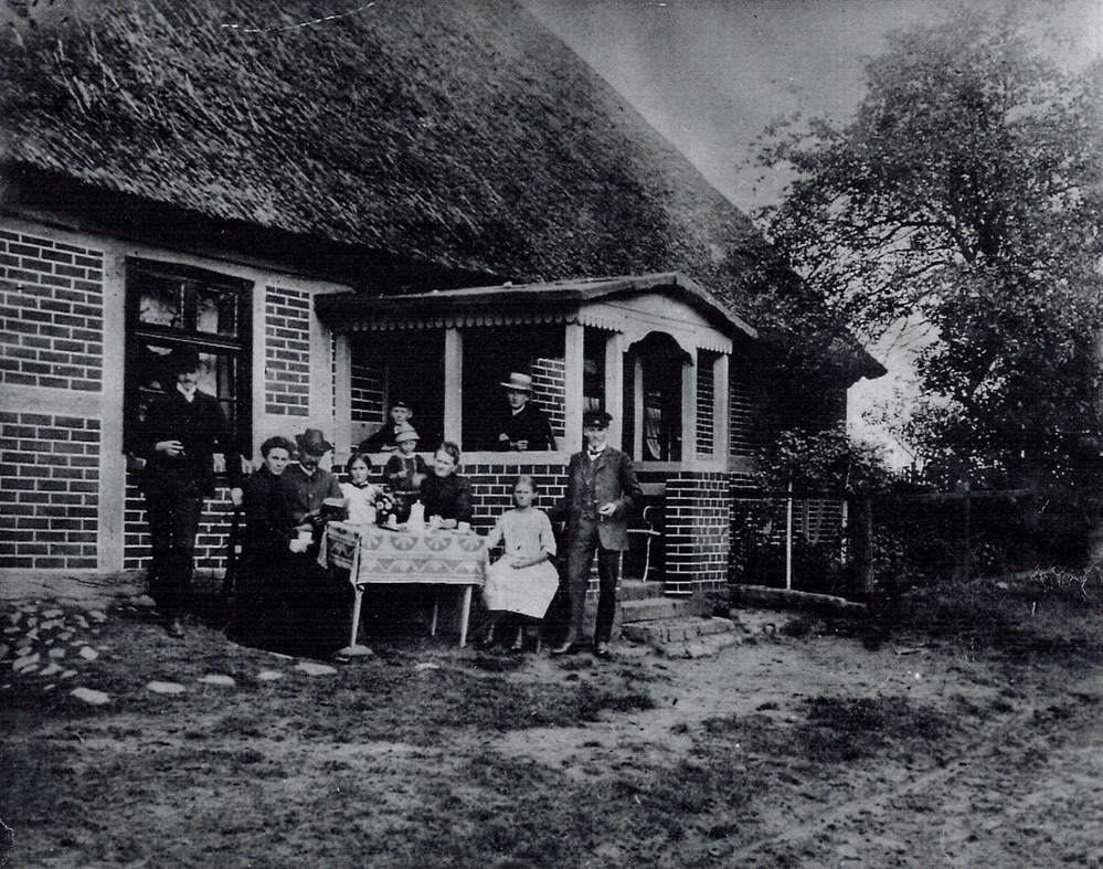 Foto von der bäuerlichen Familie vor dem schilfgedeckten Haus, um 1910